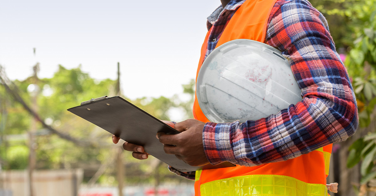 Man holding clipboard representing a contractor reviewing a construction time and material tag on the jobsite